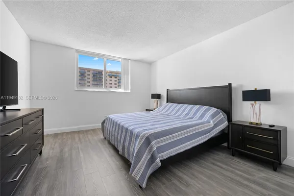 a bedroom with a bed and a flat tv screen on a dresser