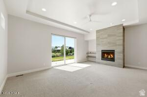 496 North Farmhouse Way, Unit 11 Midway, UT 84049 - Photo 21 of 50 Spacious room featuring a stone-clad fireplace, built-in shelving, tray ceiling, recessed lighting, and sliding glass doors opening to outdoor green space