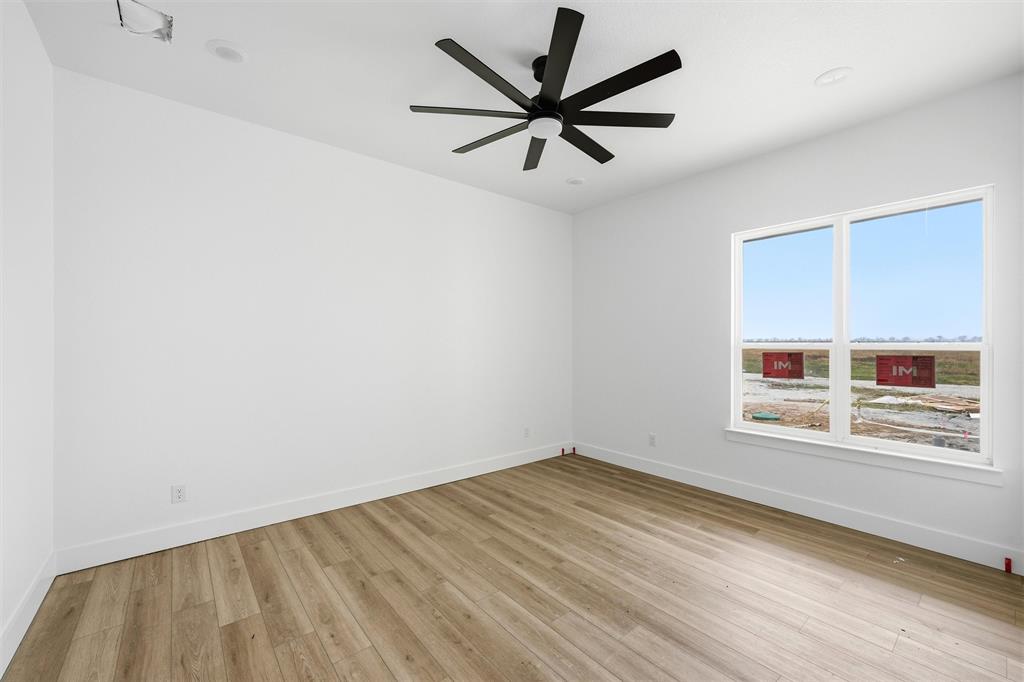 496 Willow Moon Ranch Road Crawford, TX 76638 - Photo 11 of 16 an empty room with wooden floor ceiling fan and windows