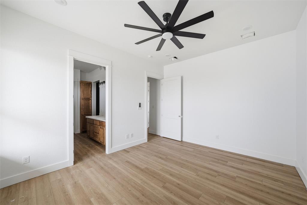 496 Willow Moon Ranch Road Crawford, TX 76638 - Photo 12 of 16 an empty room with wooden floor and ceiling fan