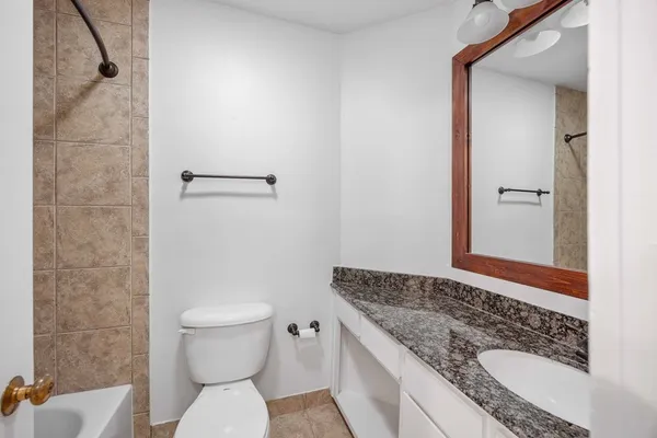 a bathroom with a granite countertop toilet a sink and a mirror