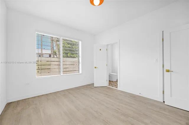 a view of an empty room with wooden floor and windows
