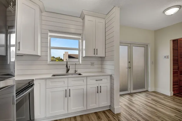 a kitchen with white cabinets and sink