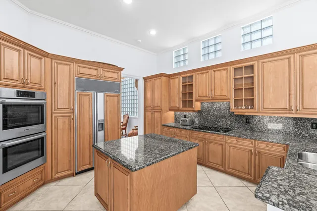 a kitchen with a stove kitchen island granite countertop a sink and cabinets