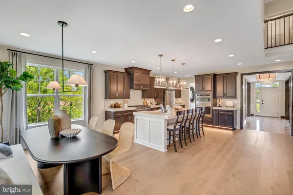 a kitchen with kitchen island a dining table chairs stainless steel appliances and windows