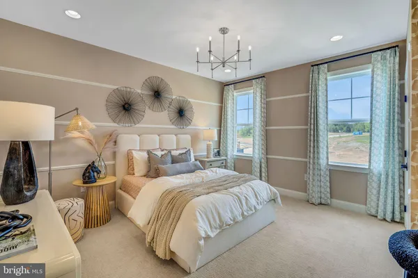 a bedroom with a bed a mirror on dresser and a chandelier