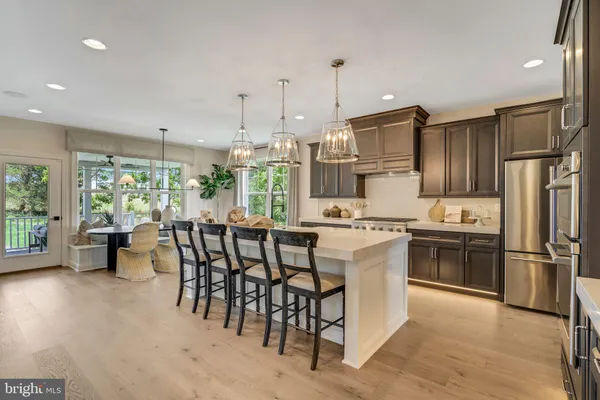 a kitchen with stainless steel appliances granite countertop a stove refrigerator and chairs