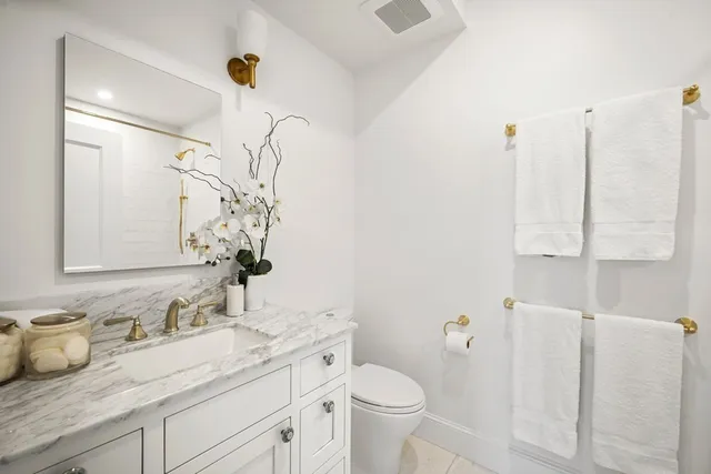 a bathroom with a granite countertop sink a toilet and a mirror