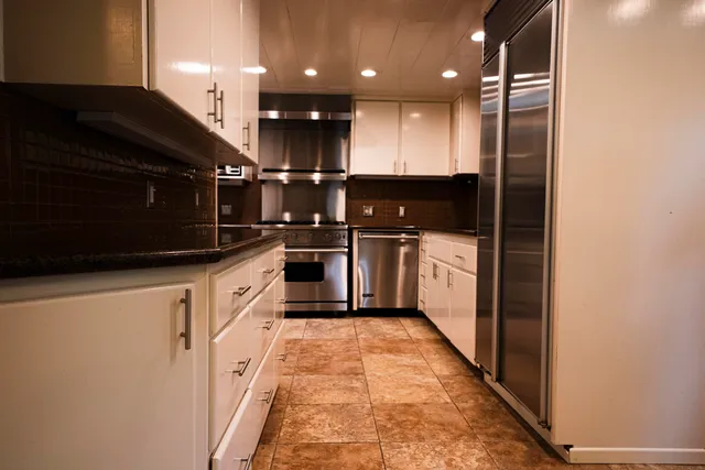 a large kitchen with stainless steel appliances granite countertop a refrigerator a sink and a stove