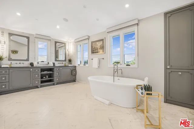 a spacious bathroom with a double vanity sink large mirror and a bathtub