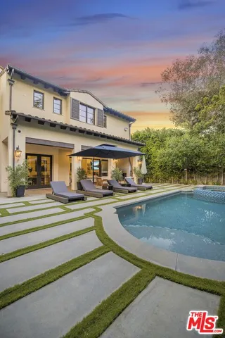 a view of house with swimming pool and a yard