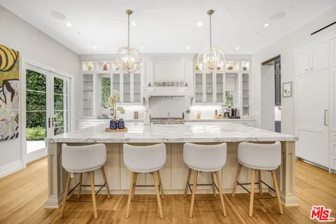 a kitchen with stainless steel appliances granite countertop a dining table chairs and white cabinets