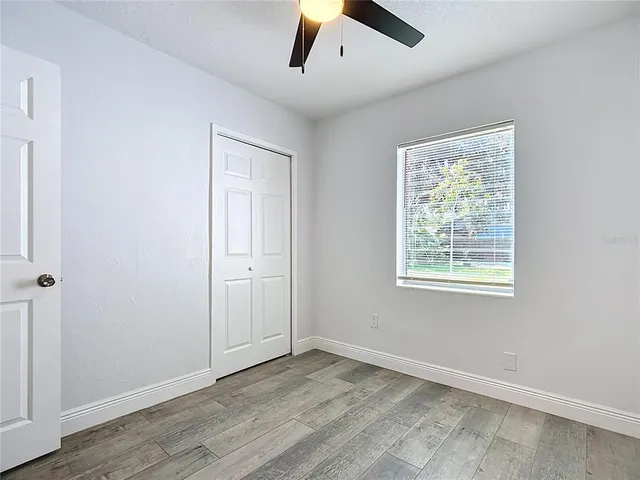 an empty room with a window and ceiling fan