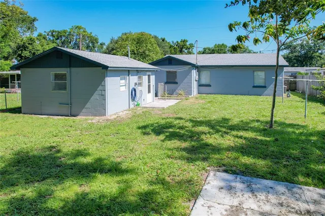 a backyard of a house with plants and large tree