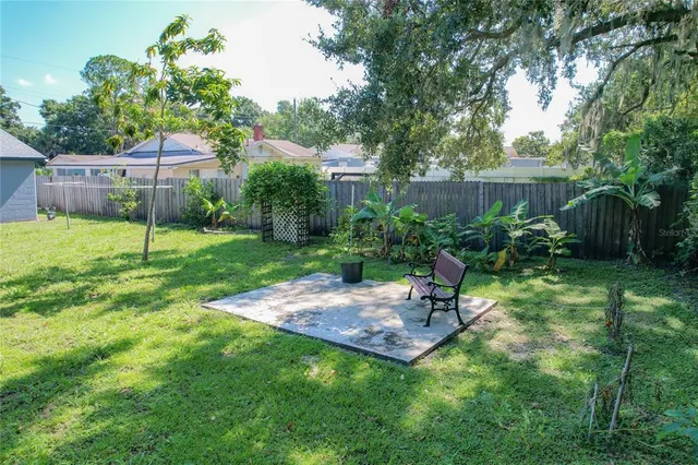 a view of a backyard with table and chairs potted plants and wooden fence