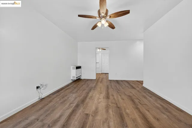 an empty room with wooden floor fan and windows