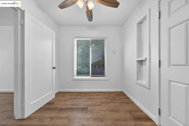 a view of an empty room with wooden floor and a window
