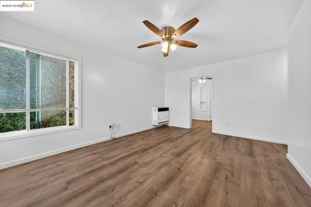 a view of empty room with wooden floor and window
