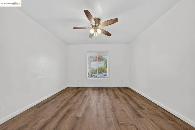 a view of room with window ceiling fan and wooden floor