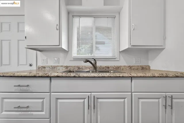 a kitchen with granite countertop white cabinets and a sink