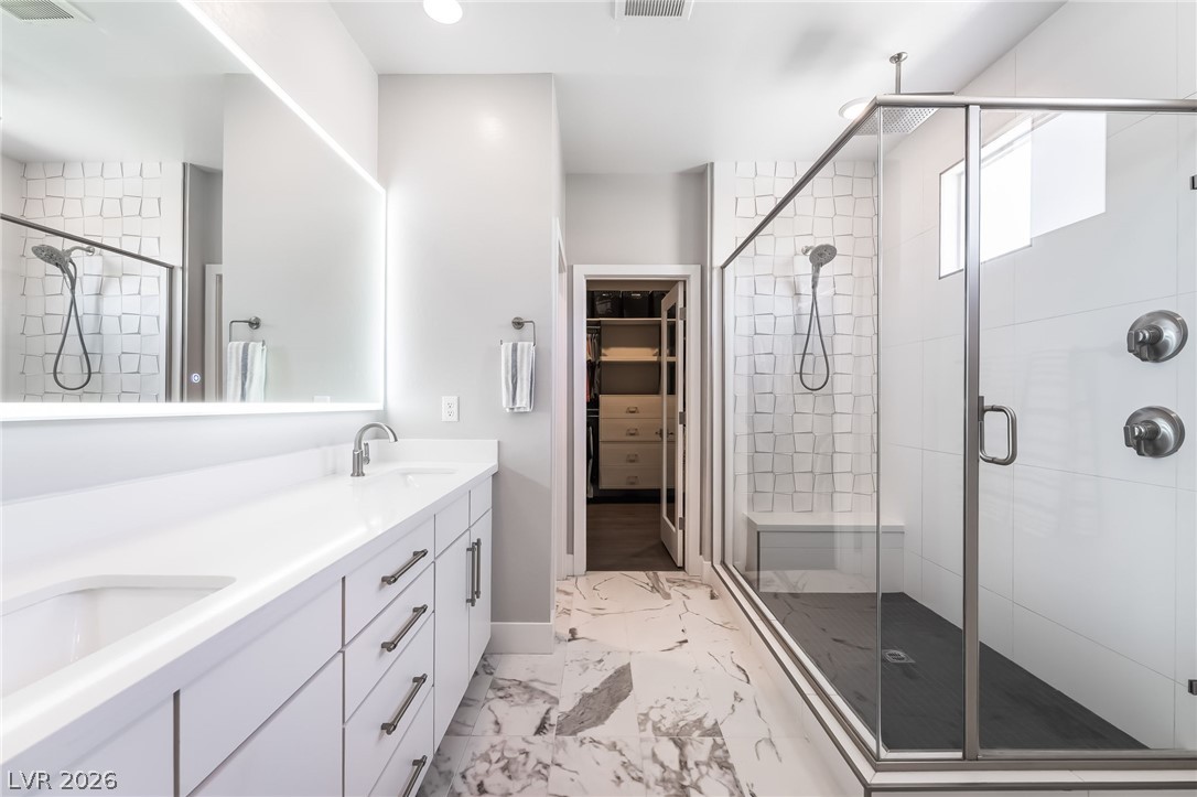 2166 Trivero Street Henderson, NV 89044 - Photo 29 of 61 A well-appointed primary bathroom featuring a large vanity, glass-enclosed shower, and direct access to a walk-in closet.