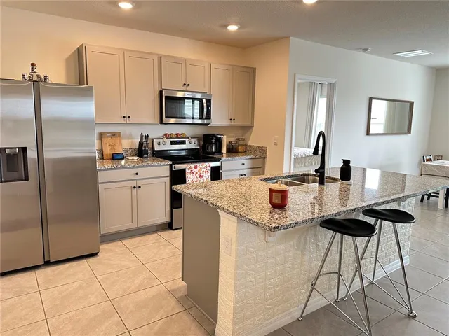 a kitchen with stainless steel appliances kitchen island granite countertop a counter top space a refrigerator a sink a counter top space and cabinets