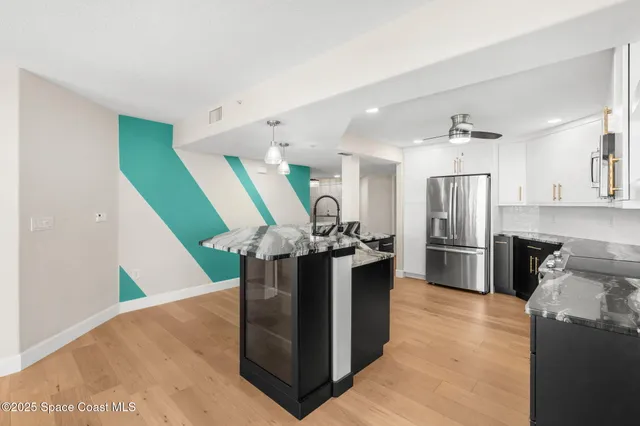 a kitchen with stainless steel appliances kitchen island granite countertop a refrigerator and a sink