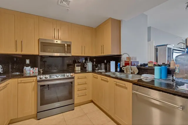 a kitchen with stainless steel appliances granite countertop a stove a sink and a microwave