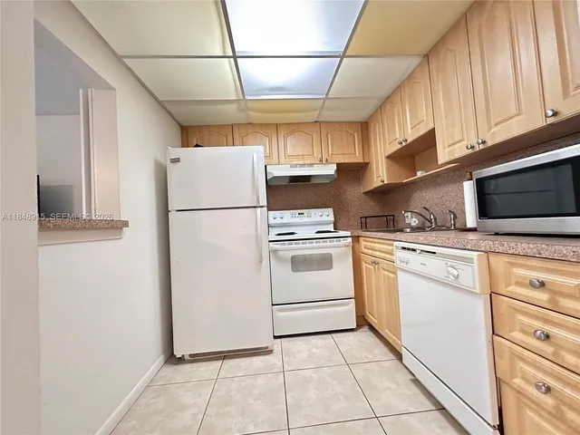 a white refrigerator freezer and a stove sitting inside of a kitchen with granite countertop a stove