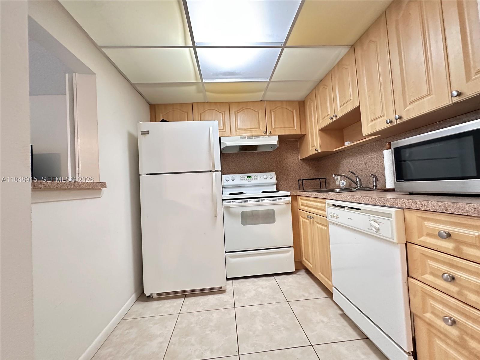 569 Fanshaw North, Unit 569 Boca Raton, FL 33434 - Photo 11 of 24 a white refrigerator freezer and a stove sitting inside of a kitchen with granite countertop a stove