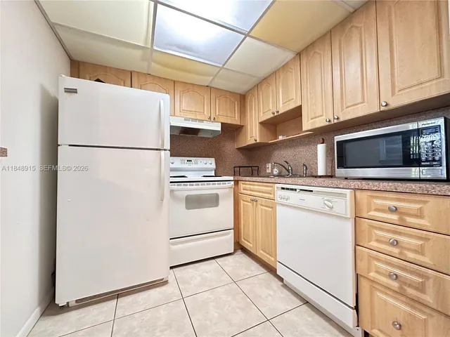 a kitchen with appliances a refrigerator and cabinets