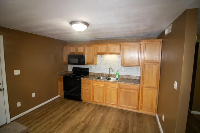 a kitchen with granite countertop stainless steel appliances a stove top oven and refrigerator