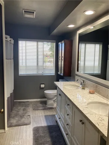 a spacious bathroom with a granite countertop sink mirror vanity and a toilet