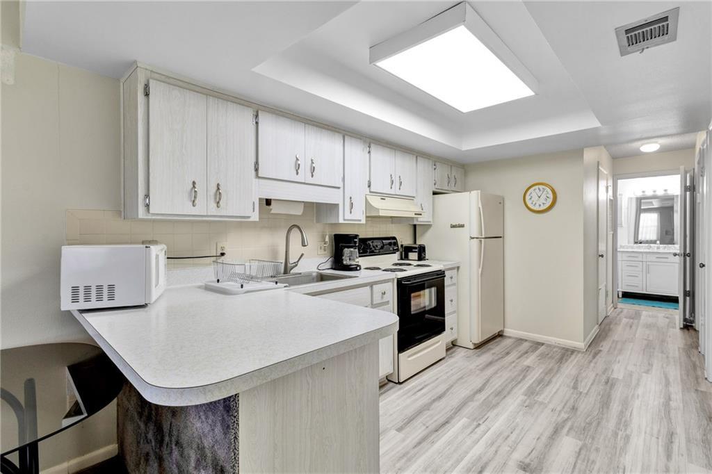 8520 Highway 1, Unit 11 Sebastian, FL 32976 - Photo 8 of 21 a kitchen with a refrigerator a stove top oven a sink and dishwasher with wooden floor