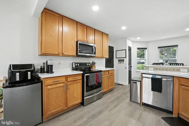 a kitchen with stainless steel appliances granite countertop a stove a sink dishwasher a refrigerator and a microwave oven with wooden floor