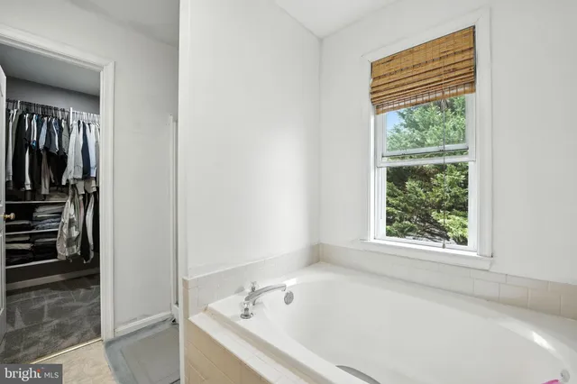 a white bath tub sitting in a bathroom next to a window