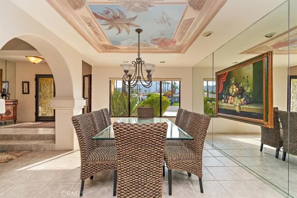 a view of a dining room with furniture a chandelier and large windows