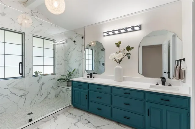 a bathroom with double vanity sinks a large mirror and a shower