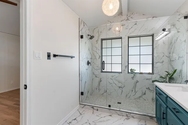 a bathroom with a granite countertop sink a large mirror and shower