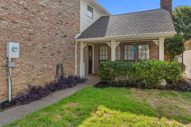 a view of a house with brick walls and a yard with plants