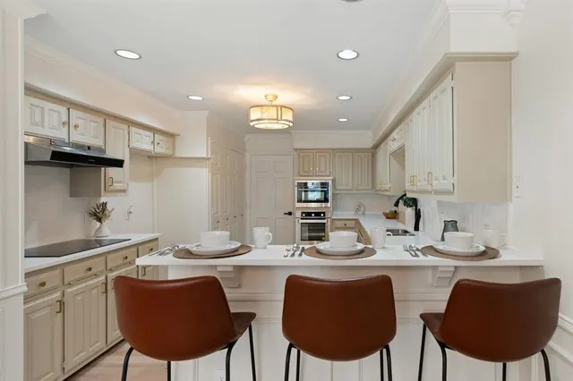 a kitchen with stainless steel appliances kitchen island granite countertop a sink a stove a kitchen island with chairs and cabinets