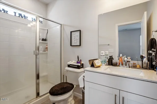 a bathroom with a sink a toilet a mirror and shower