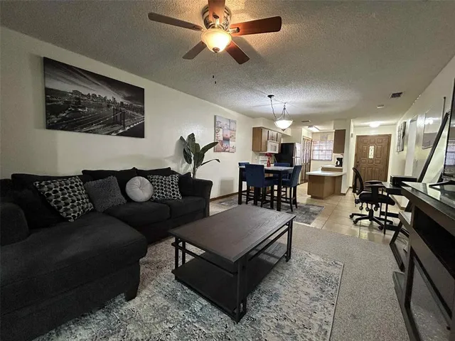 a living room with furniture kitchen view and a chandelier