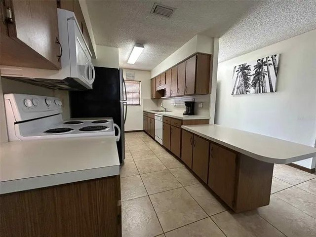 a kitchen with stainless steel appliances a sink a stove top oven a counter space and cabinets