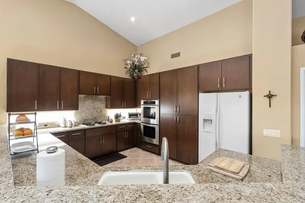 a kitchen with stainless steel appliances kitchen island granite countertop a refrigerator and a sink