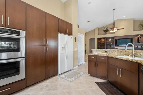 a kitchen with stainless steel appliances kitchen island granite countertop a refrigerator and a sink