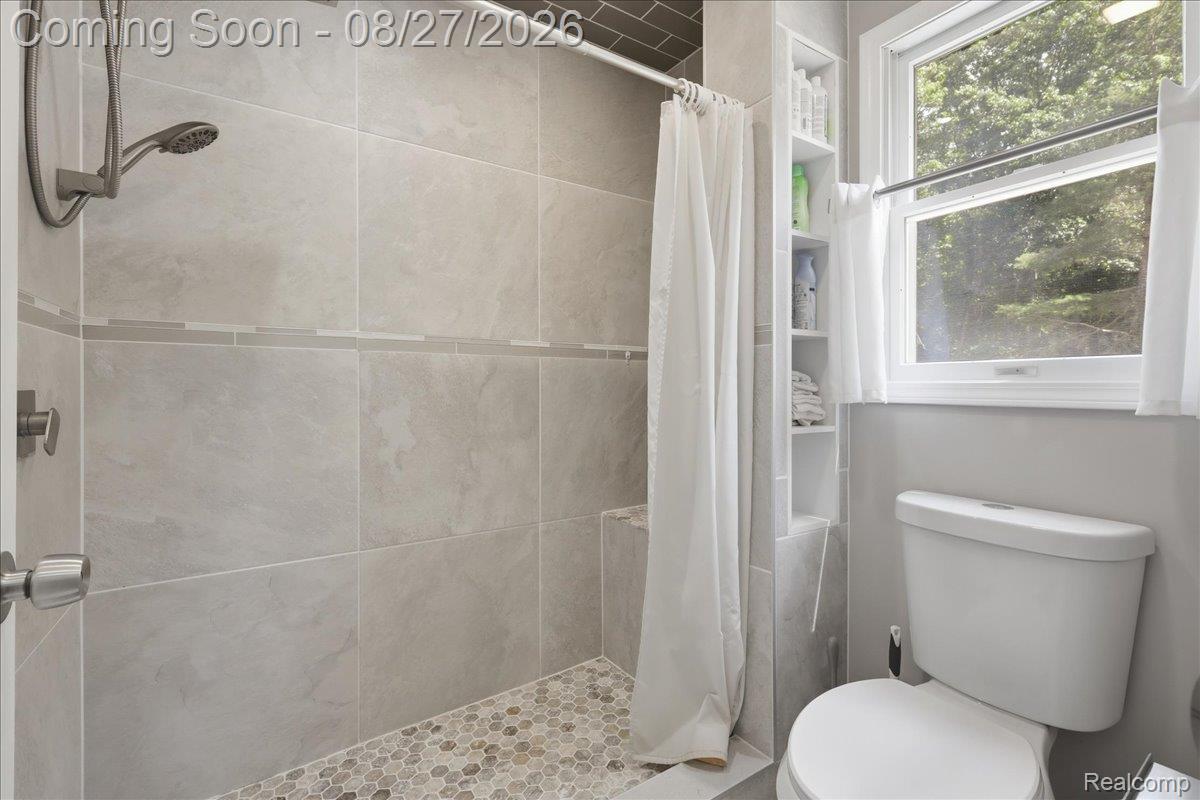 10100 Springtime Circle Clarkston, MI 48348 - Photo 36 of 73 Tiled shower with a built-in bench, mosaic floor, and a shower head with handheld sprayer