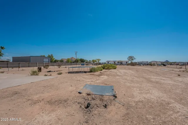 a view of a dry yard with wooden fence