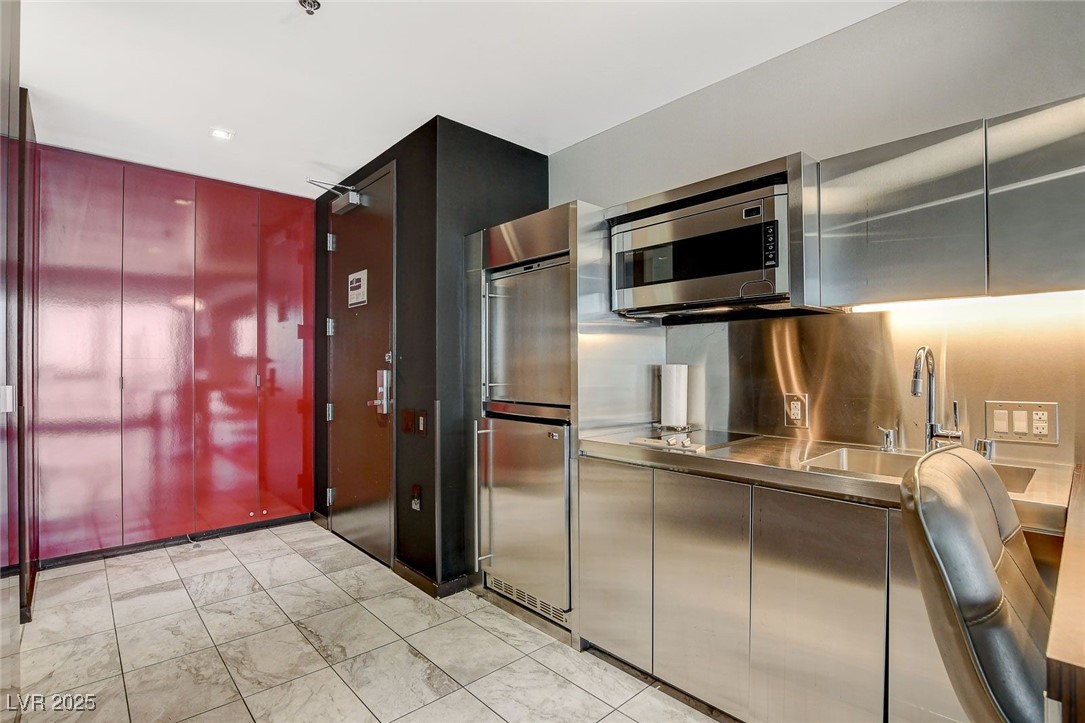 4381 West Flamingo Road, Unit 2204 Las Vegas, NV 89103 - Photo 16 of 27 Kitchen featuring stainless steel countertops, stainless steel microwave, black electric cooktop, light marble finish flooring, and refrigerator