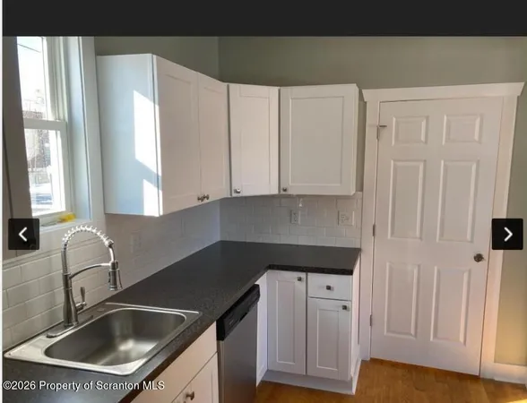 a kitchen with granite countertop white cabinets and sink